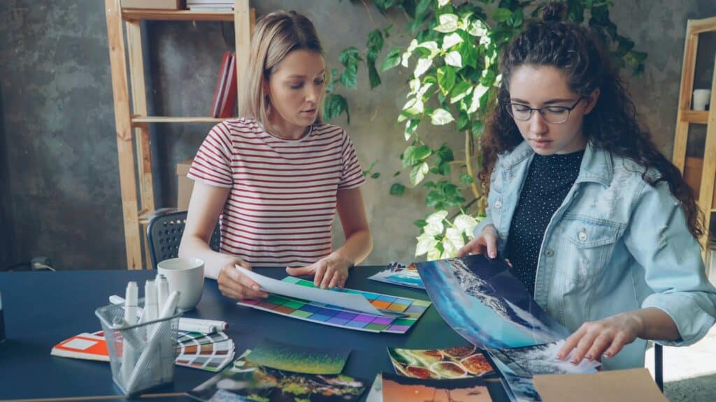 Two women working together on artwork at a table, showing the social side of crafting