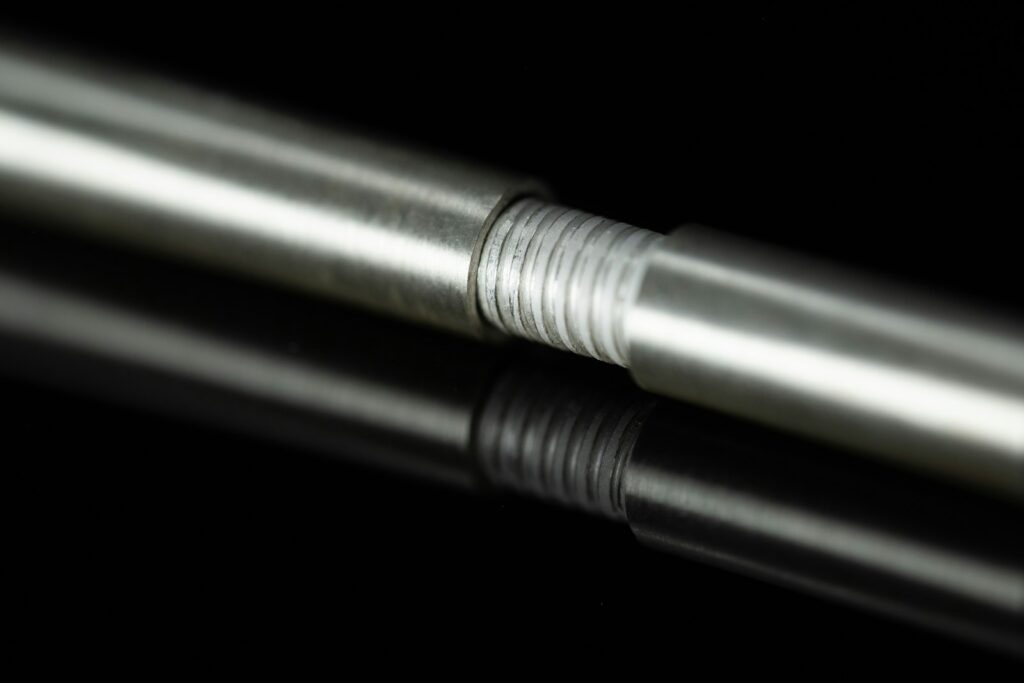 Threaded metal rod reflecting on a black surface, the sort of part chrome plating can restore
