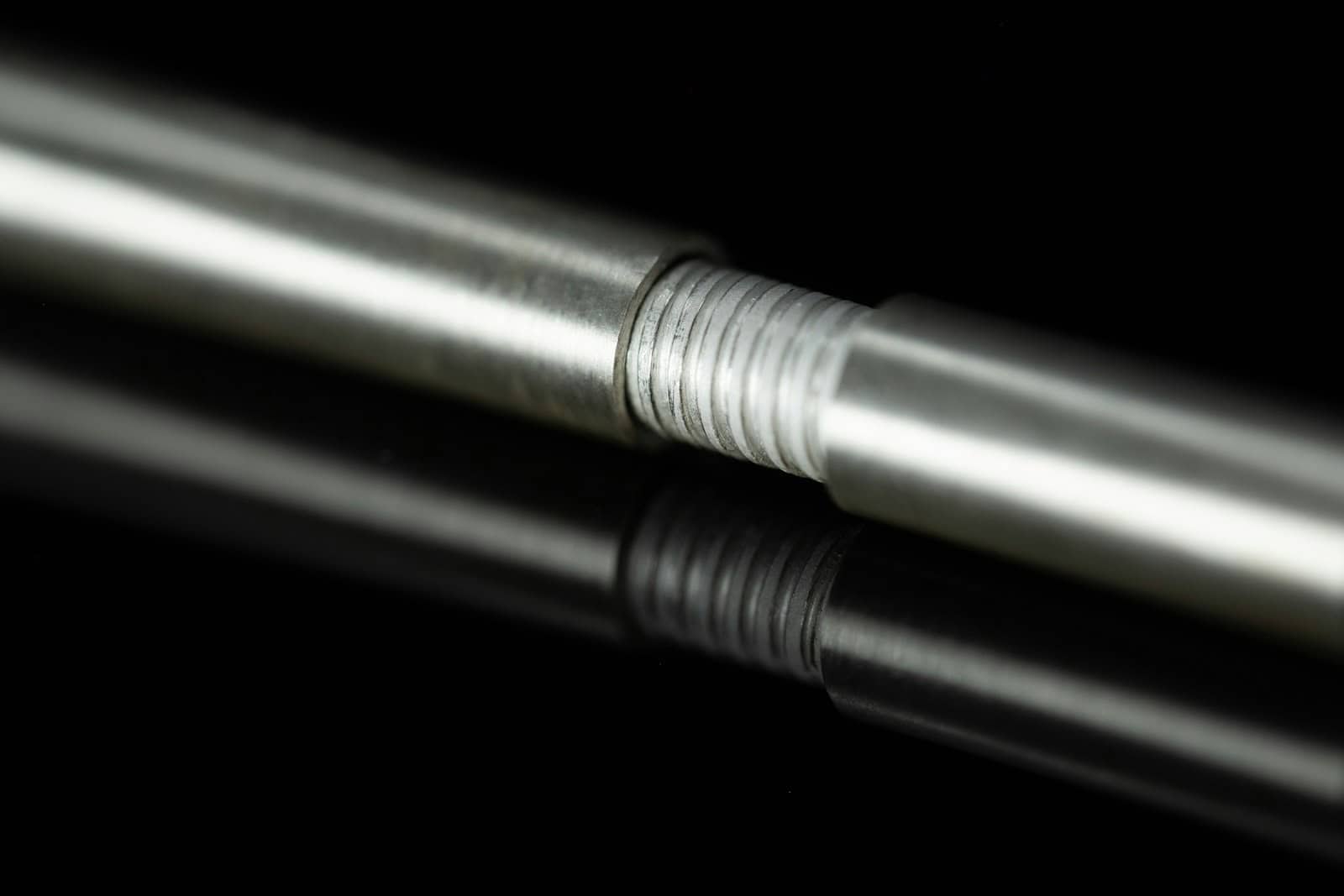Threaded metal rod reflecting on a black surface, the sort of part chrome plating can restore