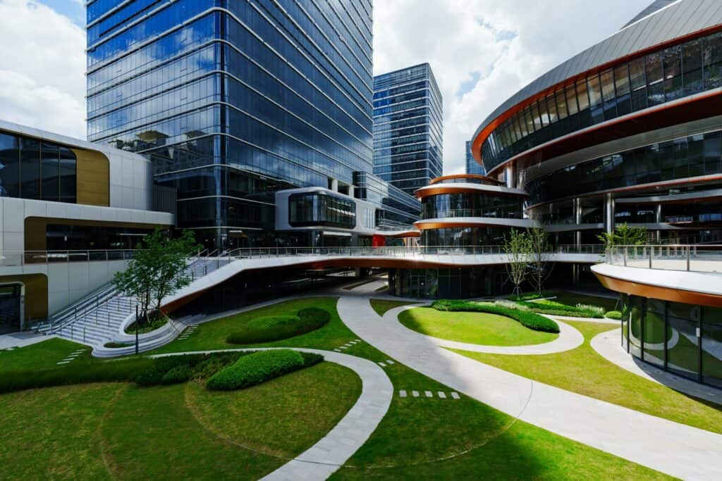 Modern glass office buildings around a landscaped courtyard with curved stone paths, showing commercial landscaping